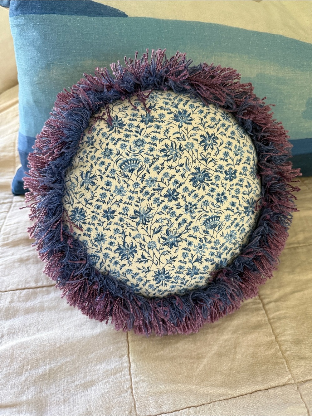 round, floral-patterned throw pillow with a purple and blue fringe border